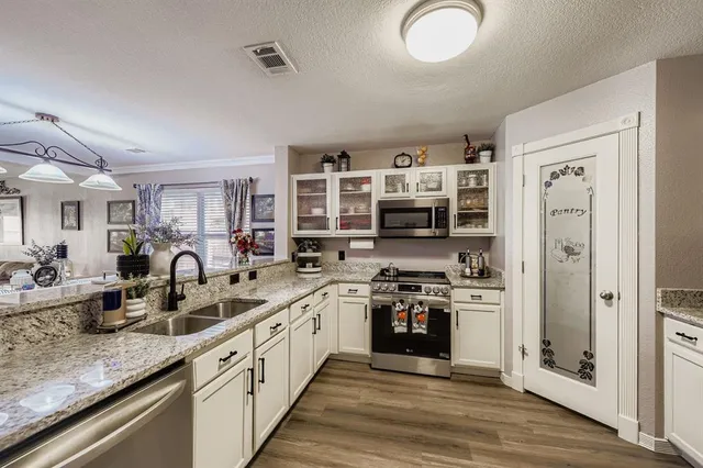 a large kitchen with stainless steel appliances granite countertop a lot of counter space and wooden floor