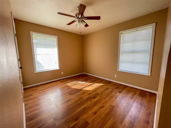 a view of an empty room with window and wooden floor