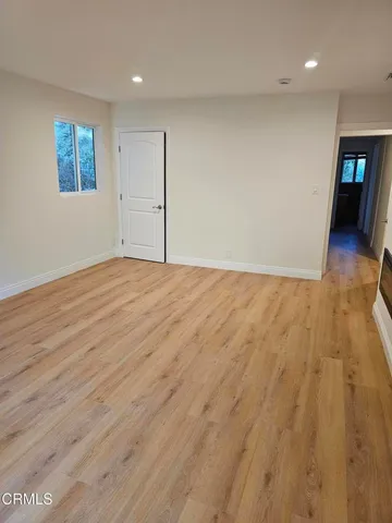 a view of an empty room with window and wooden floor