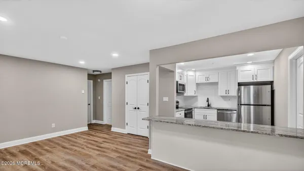 a view of kitchen with refrigerator stove and white cabinets