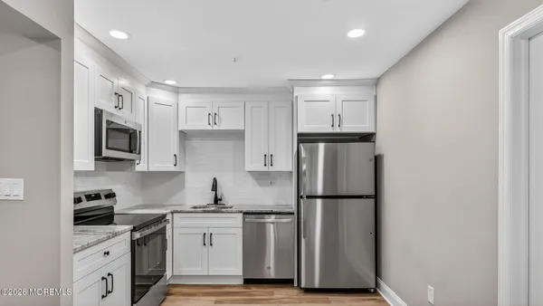 a kitchen with stainless steel appliances granite countertop a refrigerator sink and white cabinets