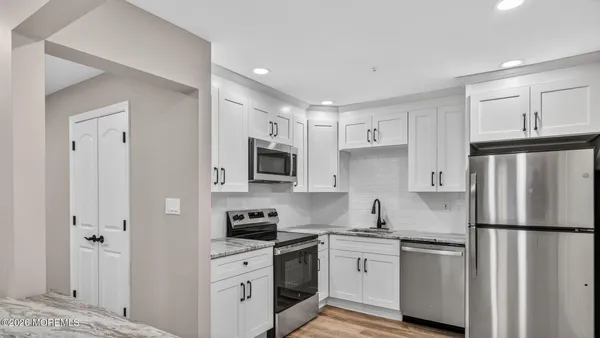 a kitchen with stainless steel appliances a refrigerator a stove a sink and white cabinets