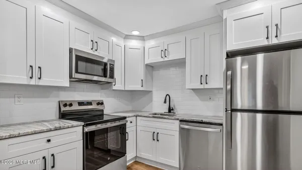 a kitchen with stainless steel appliances granite countertop a refrigerator stove a sink and dishwasher with white cabinets