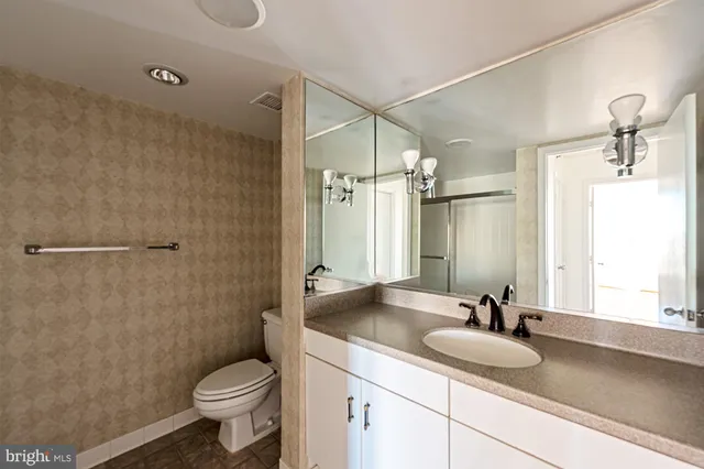 a bathroom with a granite countertop sink toilet a mirror and shower