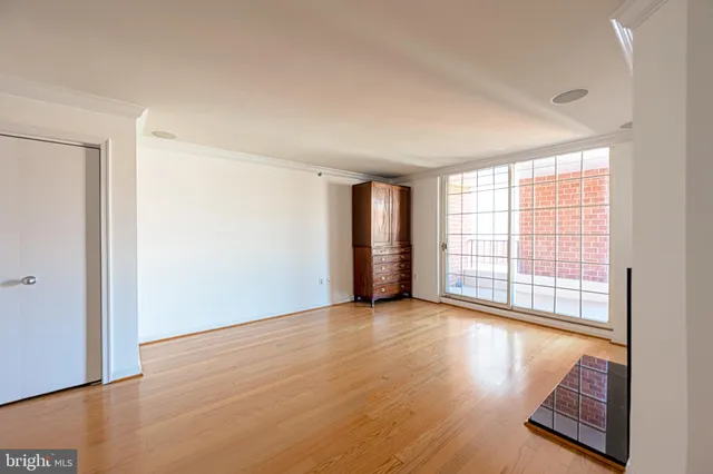 an empty room with wooden floor and windows with curtains