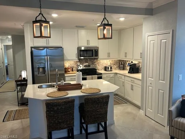 a kitchen with a refrigerator a stove a sink a dining table and chairs