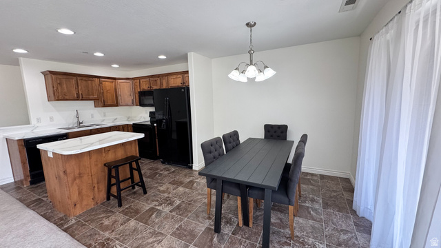 909 South Main Street, Unit F Layton, UT 84041 - Photo 3 of 21 Open-concept kitchen and dining area featuring wood cabinetry, white countertops, a central island, and black appliances