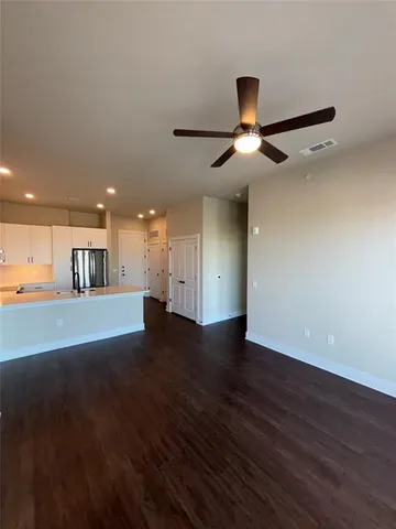 a view of an empty room with wooden floor and a ceiling fan