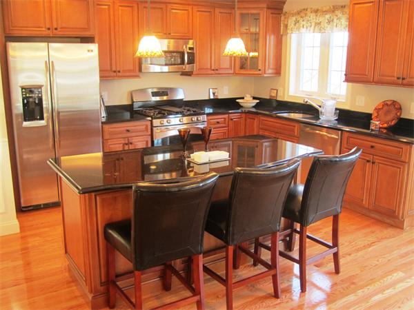 a kitchen with stainless steel appliances granite countertop a dining table chairs sink and wooden floor