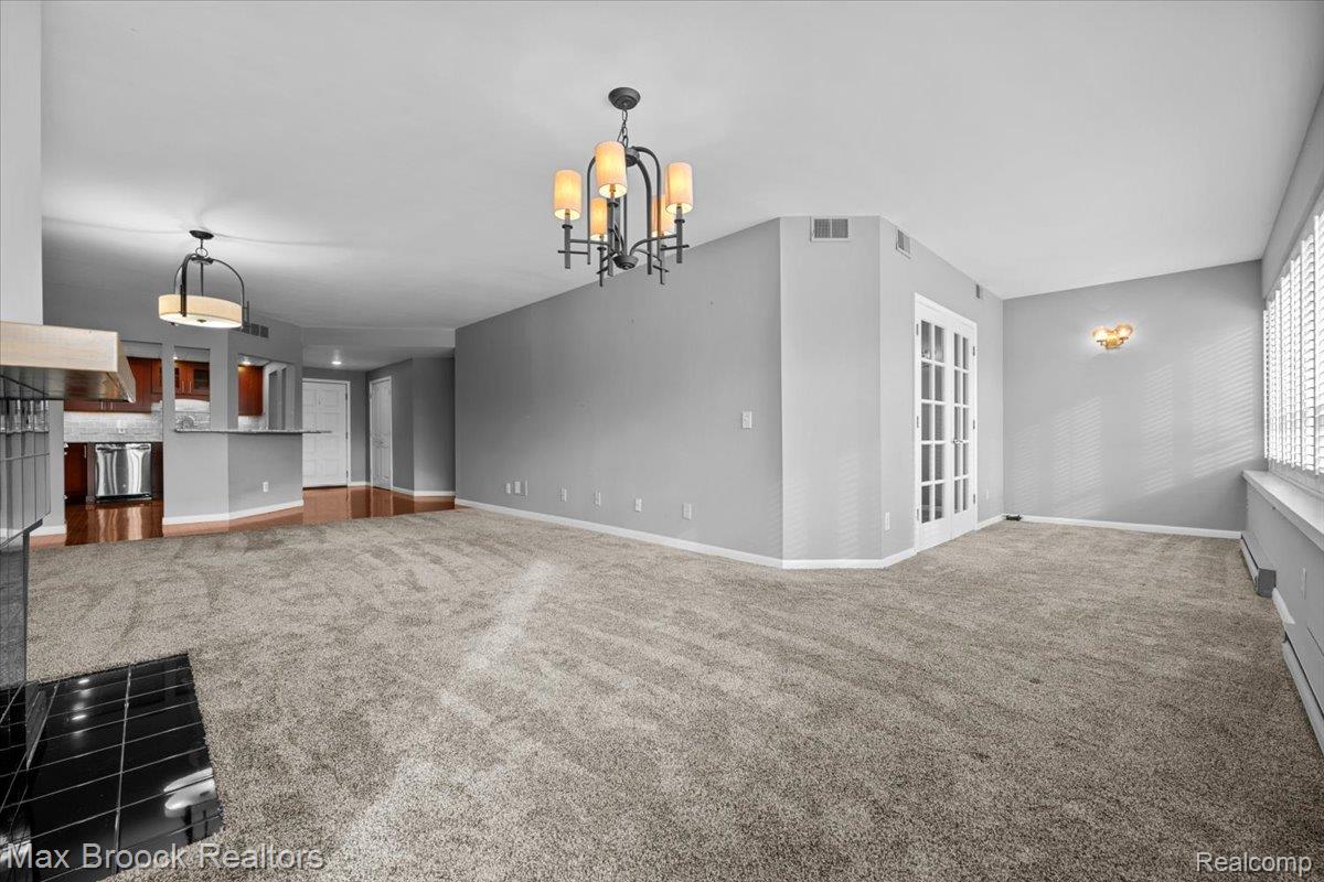 969 GreenView Court, Unit 42 Rochester, MI 48307 - Photo 14 of 41 Unfurnished living room featuring carpet flooring, hanging lights, and baseboard heating