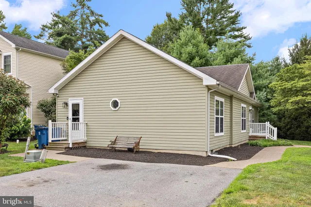 a view of a white house with a yard and plants next to a yard