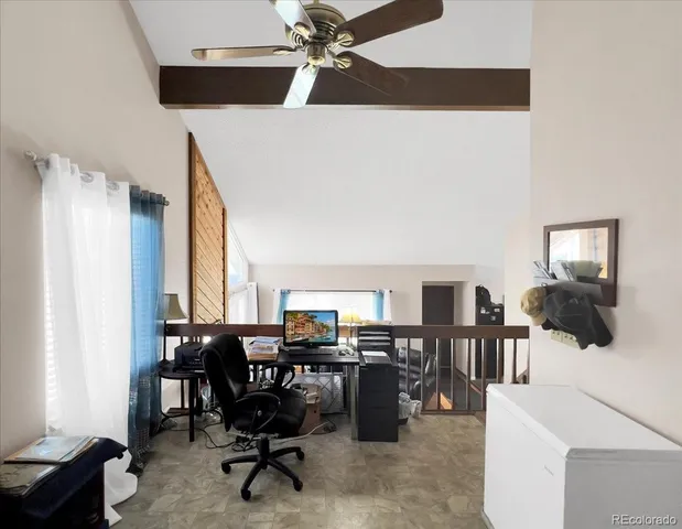 a view of a workspace with furniture and a large window