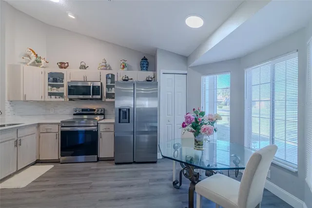 a kitchen with stainless steel appliances a dining table chairs stove refrigerator and cabinets