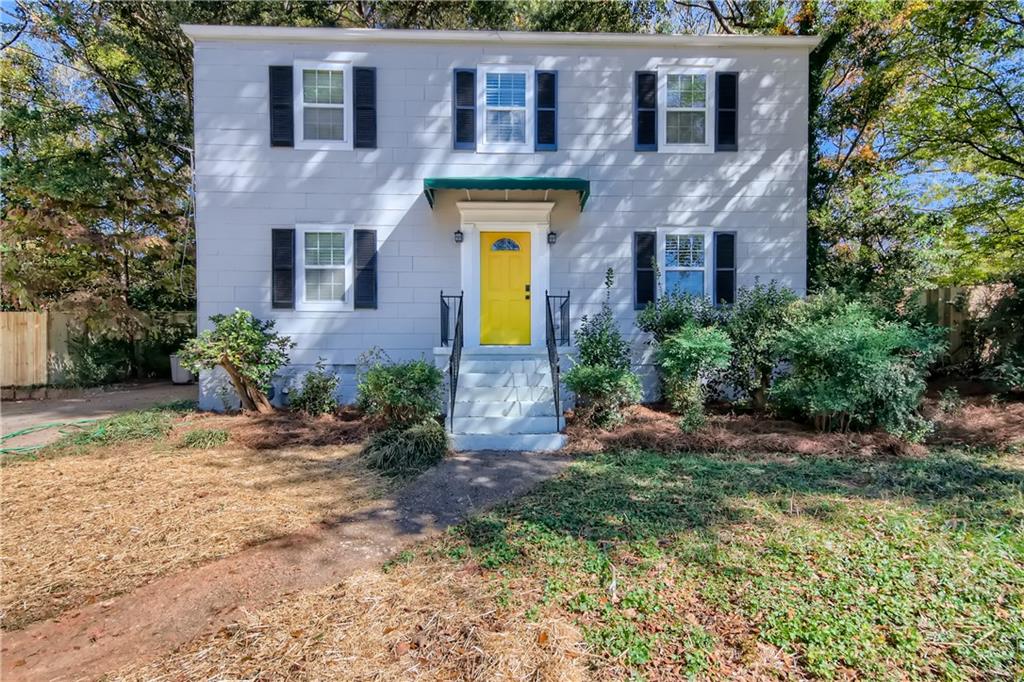 a front view of a house with yard and trees around
