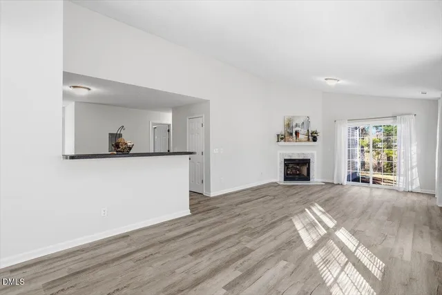 a view of a livingroom with wooden floor and a fireplace