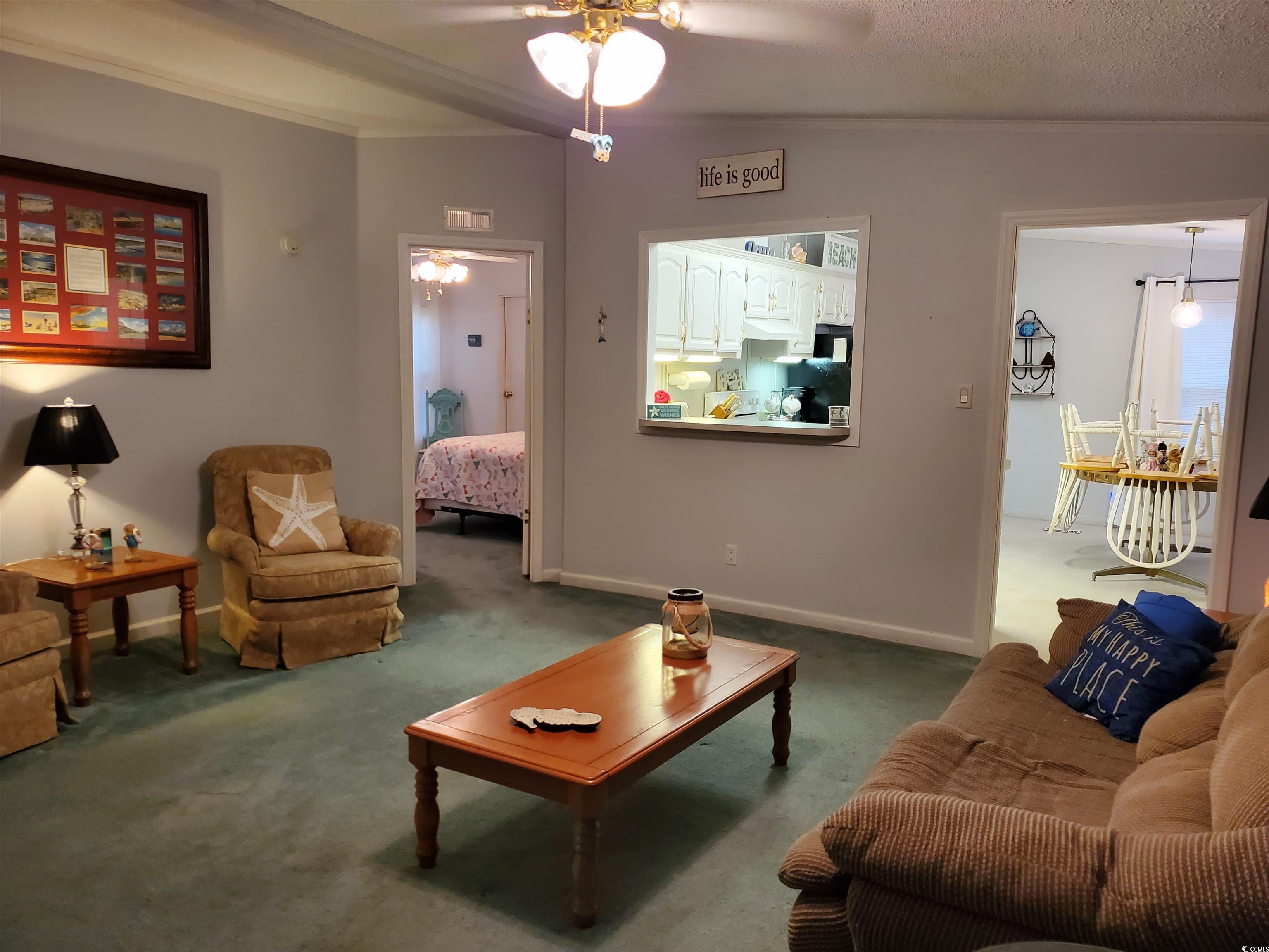 441 Delton Drive Murrells Inlet, SC 29576 - Photo 3 of 30 Living room featuring lofted ceiling, crown molding, a textured ceiling, ceiling fan, and carpet
