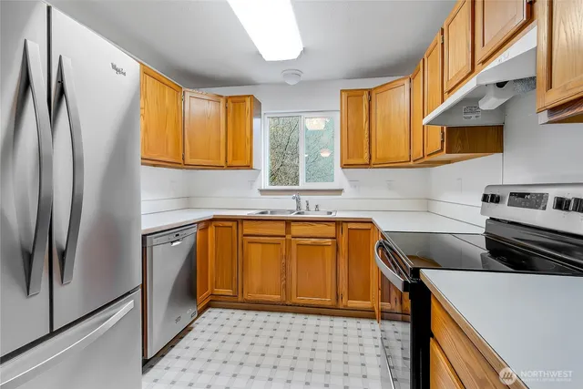 a kitchen with stainless steel appliances granite countertop a refrigerator and a sink