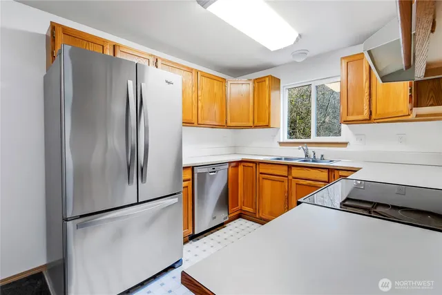 a kitchen with stainless steel appliances a refrigerator sink and wooden cabinets