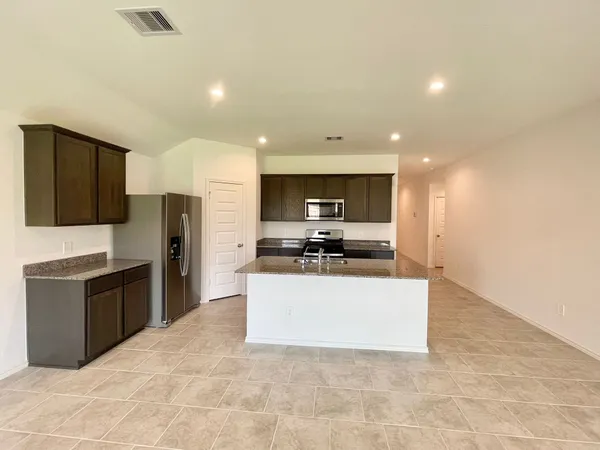 a large kitchen with a large counter top stainless steel appliances and cabinets
