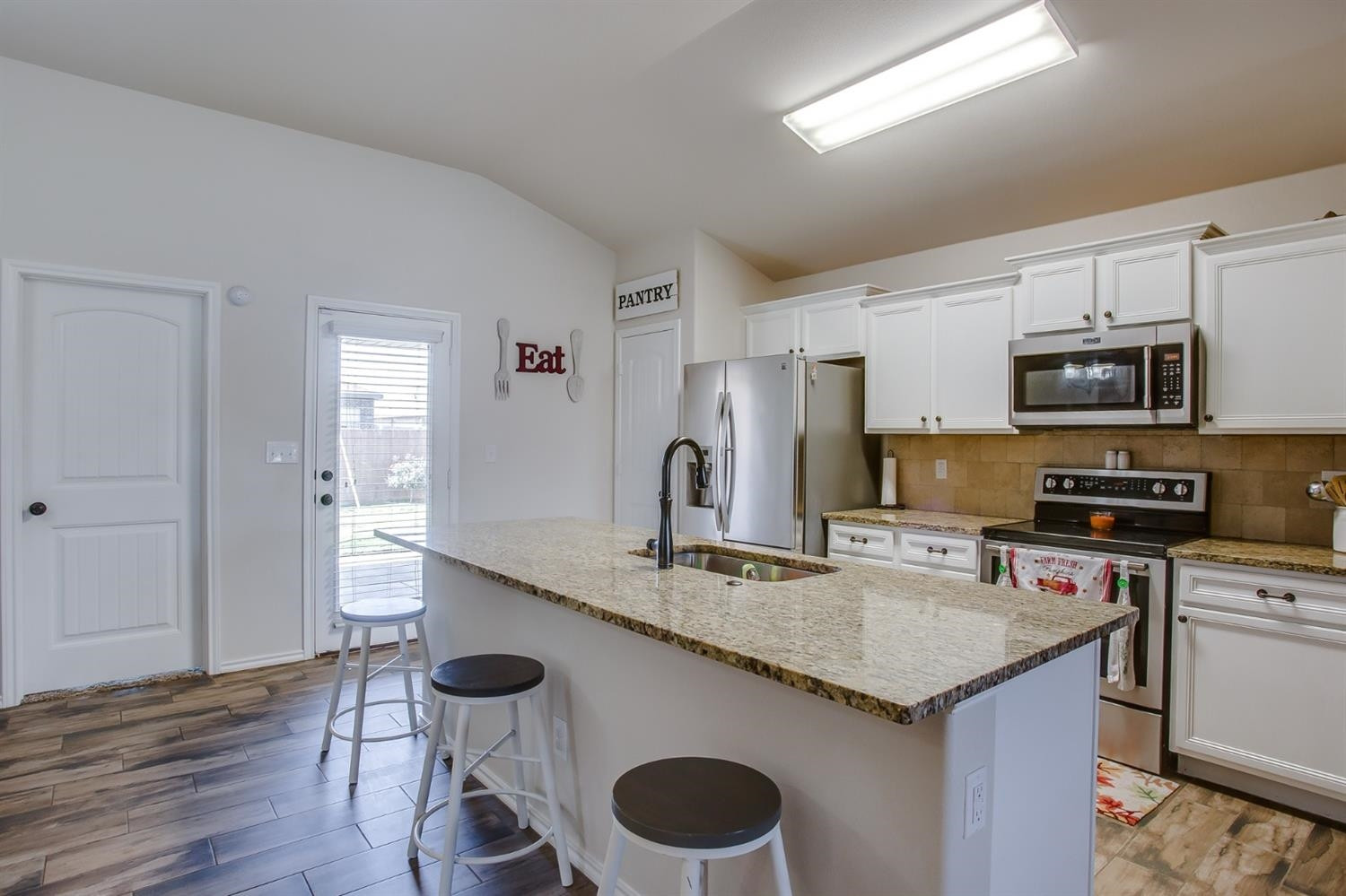 7449 104th Street Lubbock, TX 79424 - Photo 4 of 16 a kitchen with stainless steel appliances granite countertop a sink stove microwave and cabinets