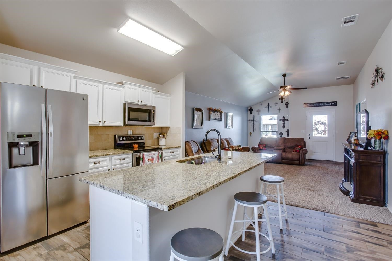 7449 104th Street Lubbock, TX 79424 - Photo 6 of 16 a kitchen with a refrigerator a stove a dining table and chairs with wooden floor