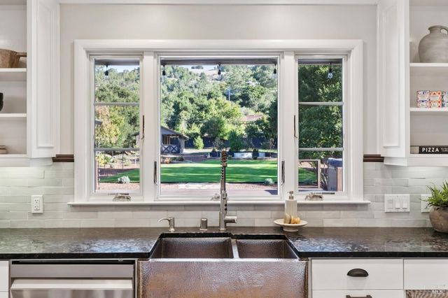 a kitchen with granite countertop a sink window and cabinets