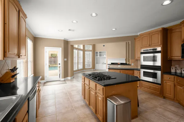 a kitchen with stainless steel appliances granite countertop a stove top oven a sink dishwasher a refrigerator and cabinets with wooden floor