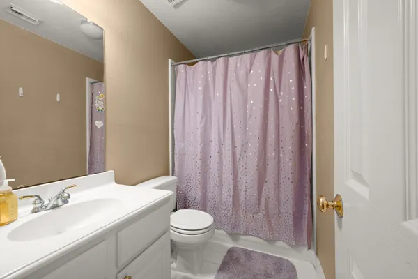 a bathroom with a sink a toilet and shower curtain