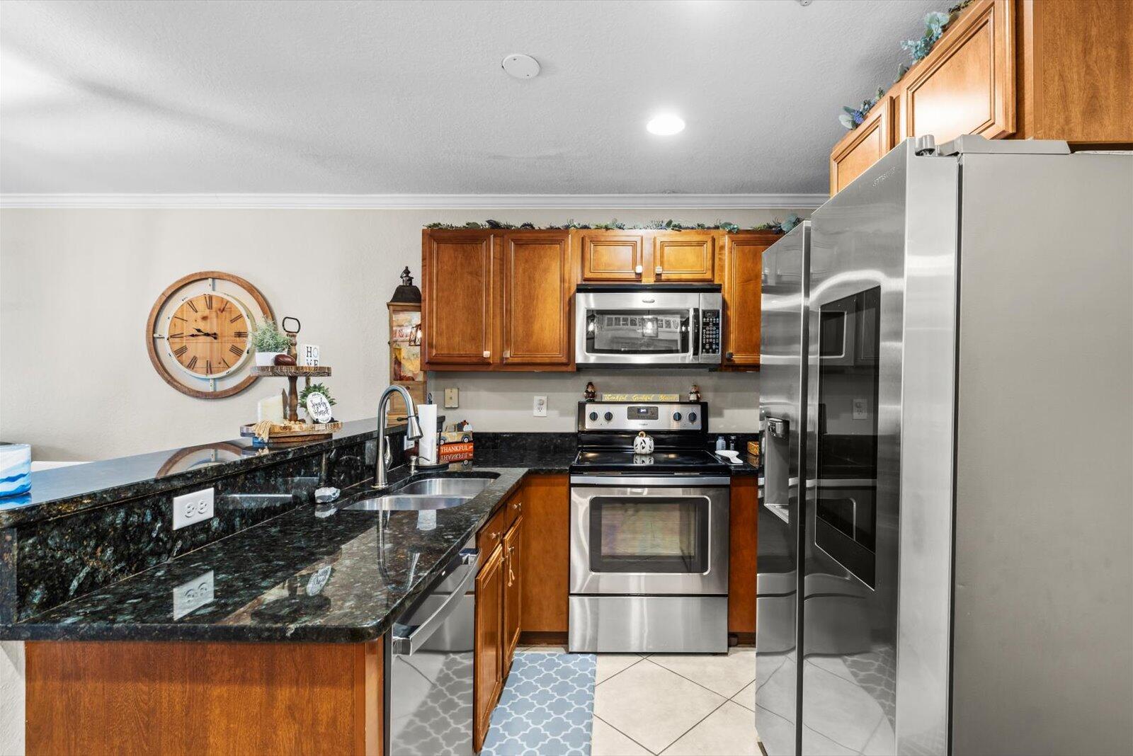 5290 Southeast Mitchell Lane Stuart, FL 34997 - Photo 10 of 43 a kitchen with stainless steel appliances granite countertop a stove top oven a sink and a refrigerator
