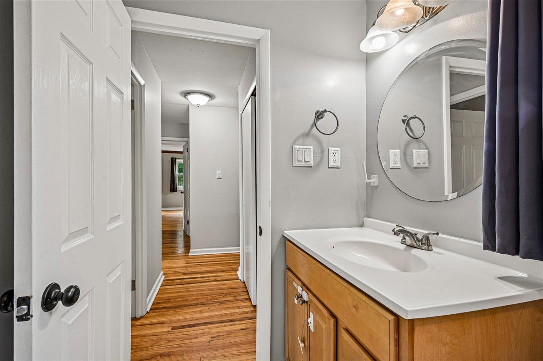 2428 Nottingham Road Bethlehem, PA 18017 - Photo 21 of 48 A well-appointed bathroom vanity with natural wood cabinetry and a sleek countertop awaits, alongside rich hardwood flooring in the adjacent hallway.