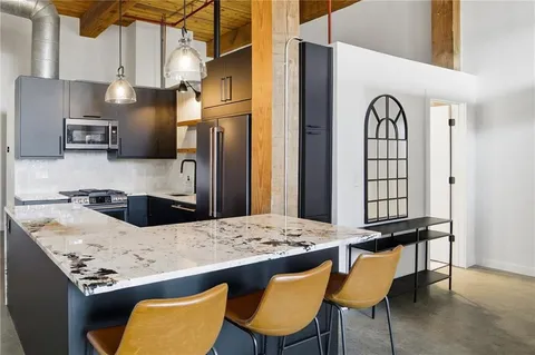a kitchen with stainless steel appliances kitchen island a table chairs in it and wooden floors