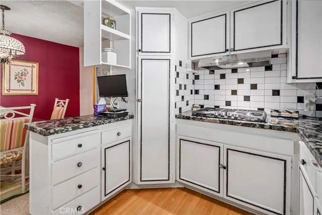 a kitchen with granite countertop white cabinets and stainless steel appliances