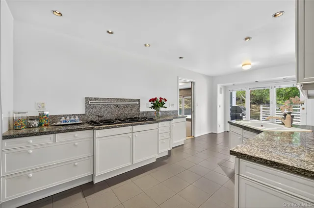 a large kitchen with granite countertop a sink and white cabinets