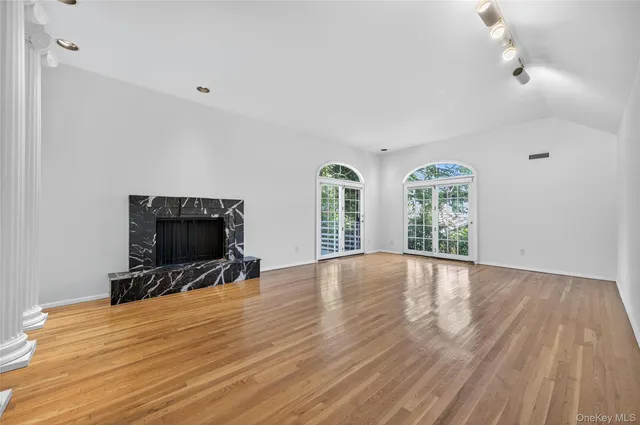 a view of an empty room with a window and wooden floor