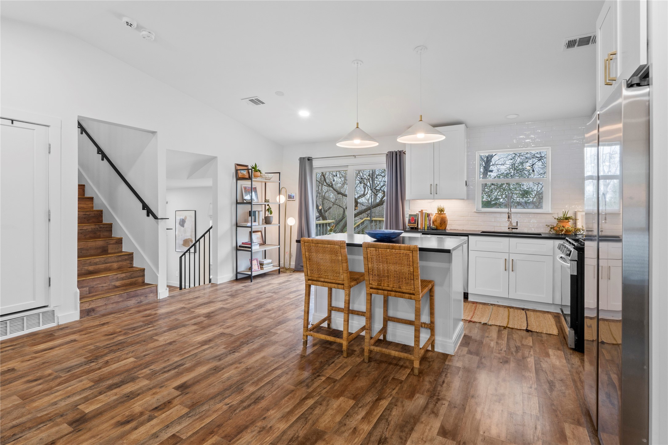 6809 Roanoke Drive Austin, TX 78723 - Photo 4 of 25 Kitchen with white cabinets, hanging light fixtures, a kitchen island, stainless steel appliances, and a breakfast bar