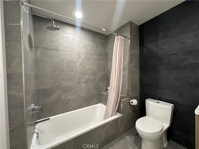 a white toilet sitting next to a bath tub and a shower