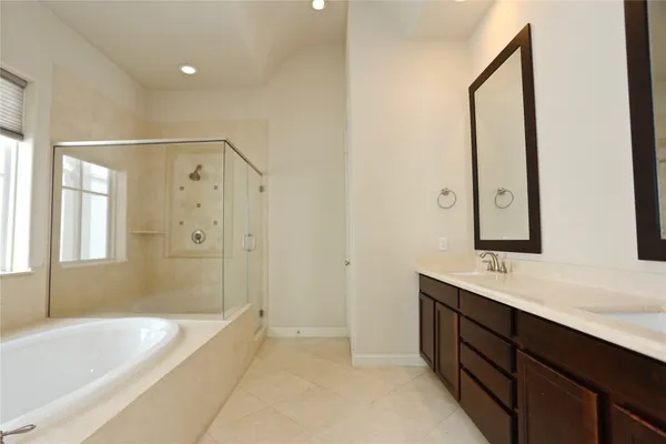 a bathroom with a double vanity sink a mirror a bathtub and shower