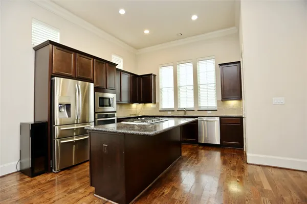 a kitchen with stainless steel appliances granite countertop a refrigerator a sink dishwasher a stove and white countertops with wooden floor