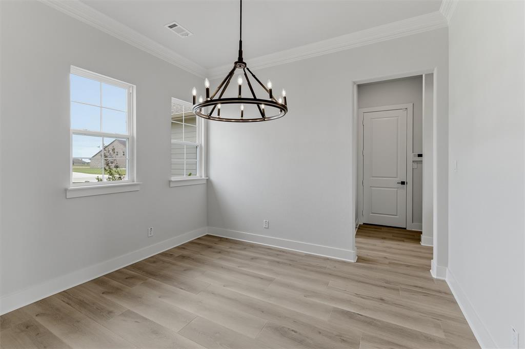 2204 Continent Court Krum, TX 76249 - Photo 6 of 28 Room featuring wood-finish flooring, two windows with white trim, a contemporary black metal chandelier, and a doorway with a panel door