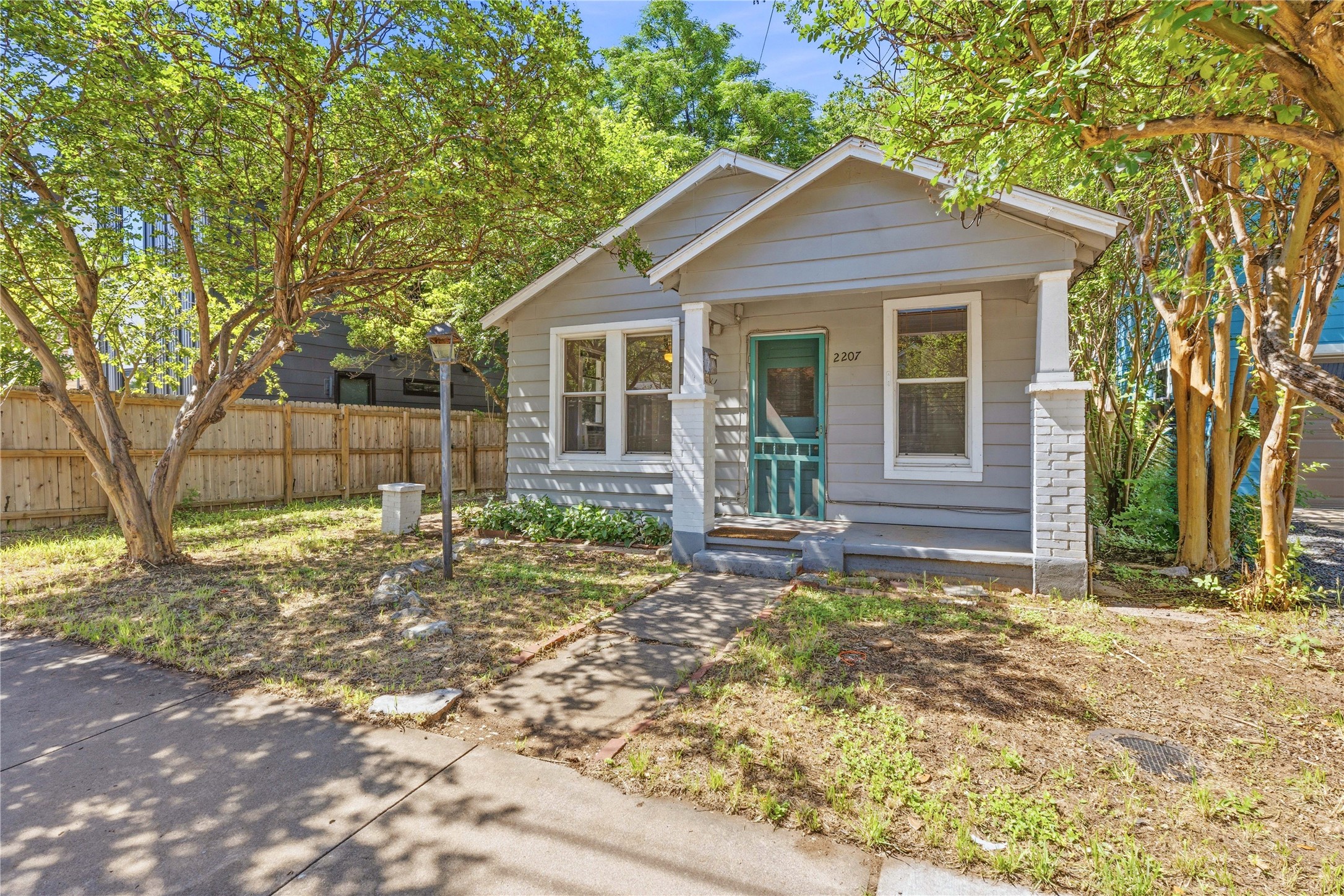 2207 Santa Rita Street Austin, TX 78702 - Photo 15 of 15 Gray exterior siding with white trim, featuring a screened front door and stone-clad porch columns