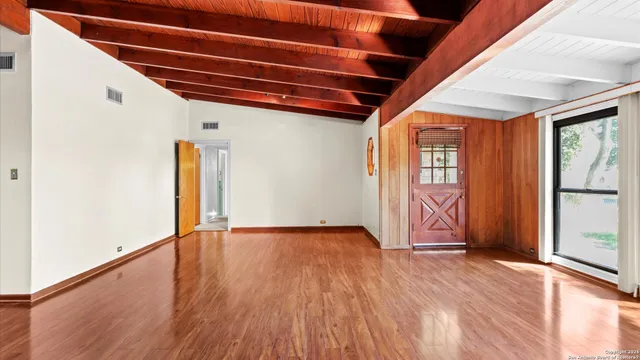 an empty room with wooden floor fireplace and windows