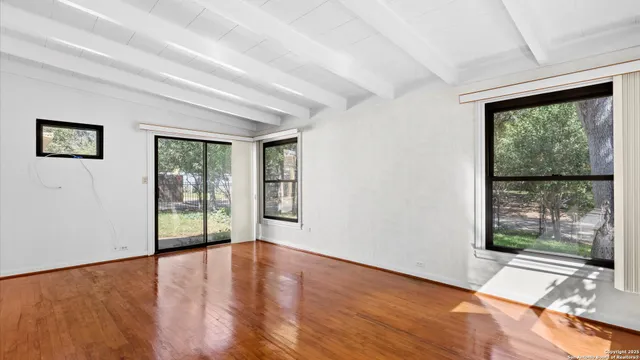 a view of an empty room with wooden floor and a window