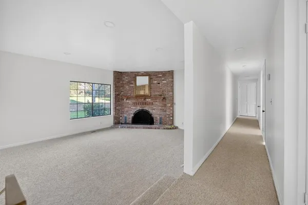 an empty room with windows and fireplace