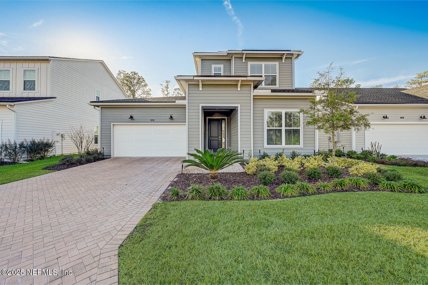 a front view of a house with a yard and potted plants