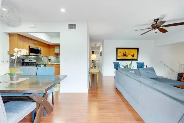 a living room with stainless steel appliances furniture a rug and a view of kitchen