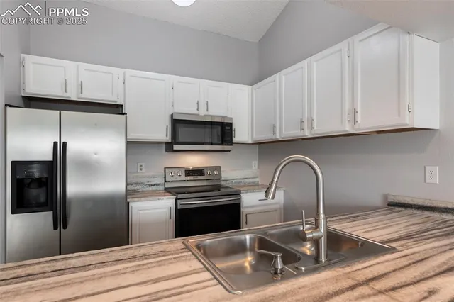 a kitchen with granite countertop a sink stainless steel appliances and white cabinets