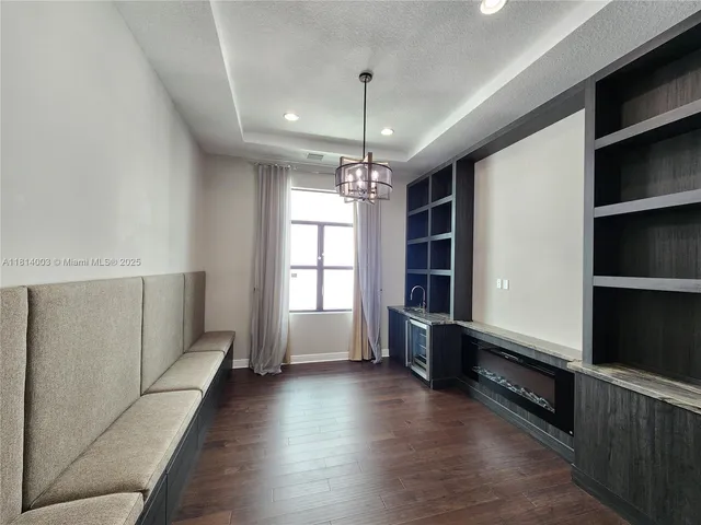 a view of an empty room with a floor to ceiling window and chandelier