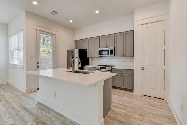 a kitchen with kitchen island a sink appliances and cabinets