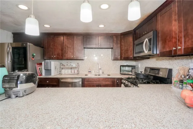 a kitchen with stainless steel appliances granite countertop wooden cabinets a stove top oven a sink and dishwasher