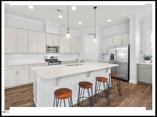 a dining hall with stainless steel appliances kitchen island granite countertop a dining table chairs and view living room